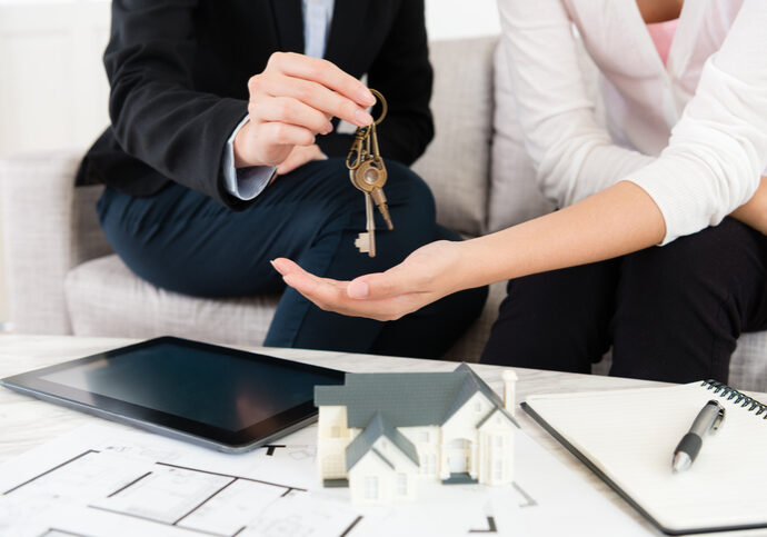 closeup photo of saleswoman giving house key escrow and closing Wilcox